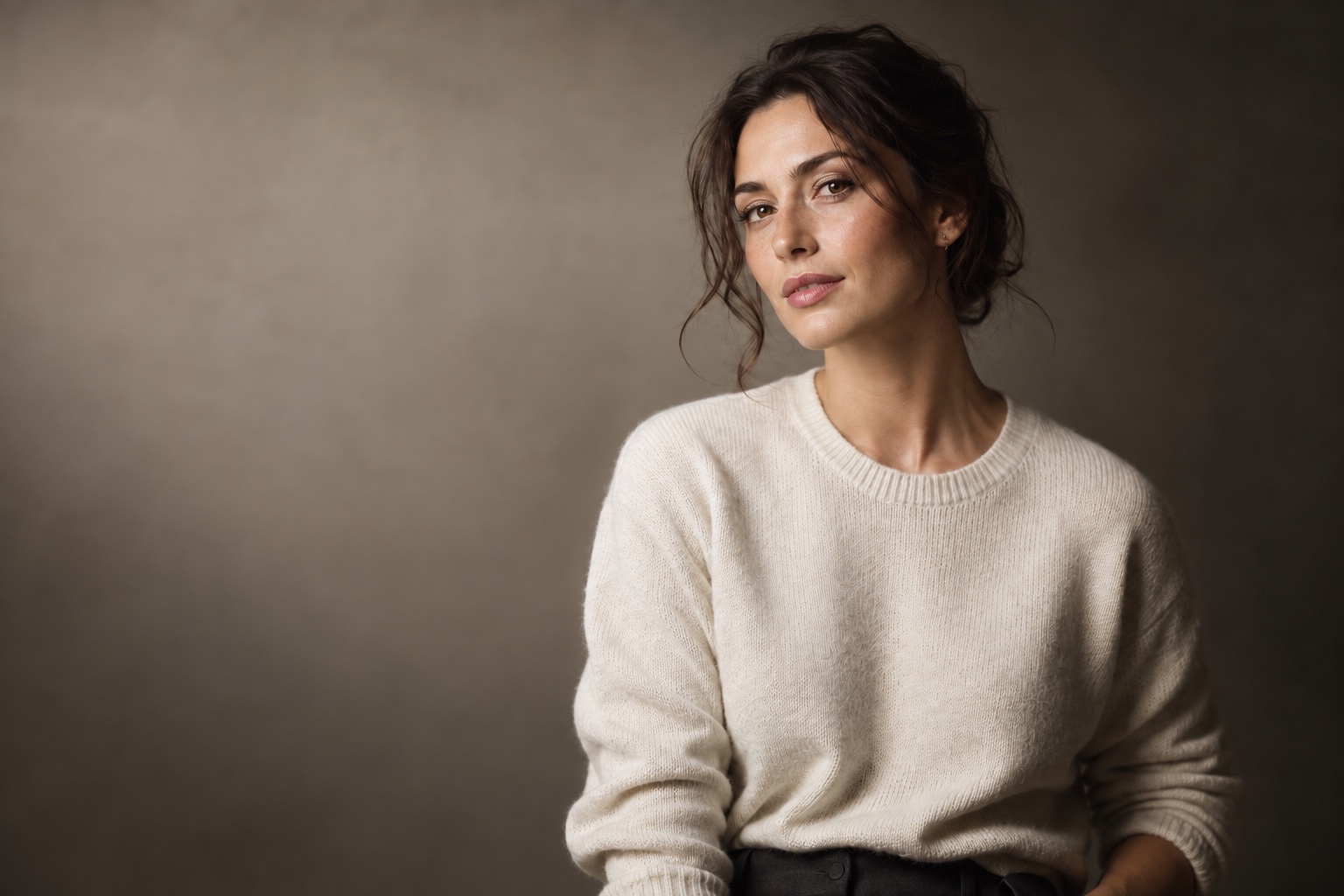 Editorial portrait with soft one-light shaping, a gentle cheek shadow, and a darker neutral background